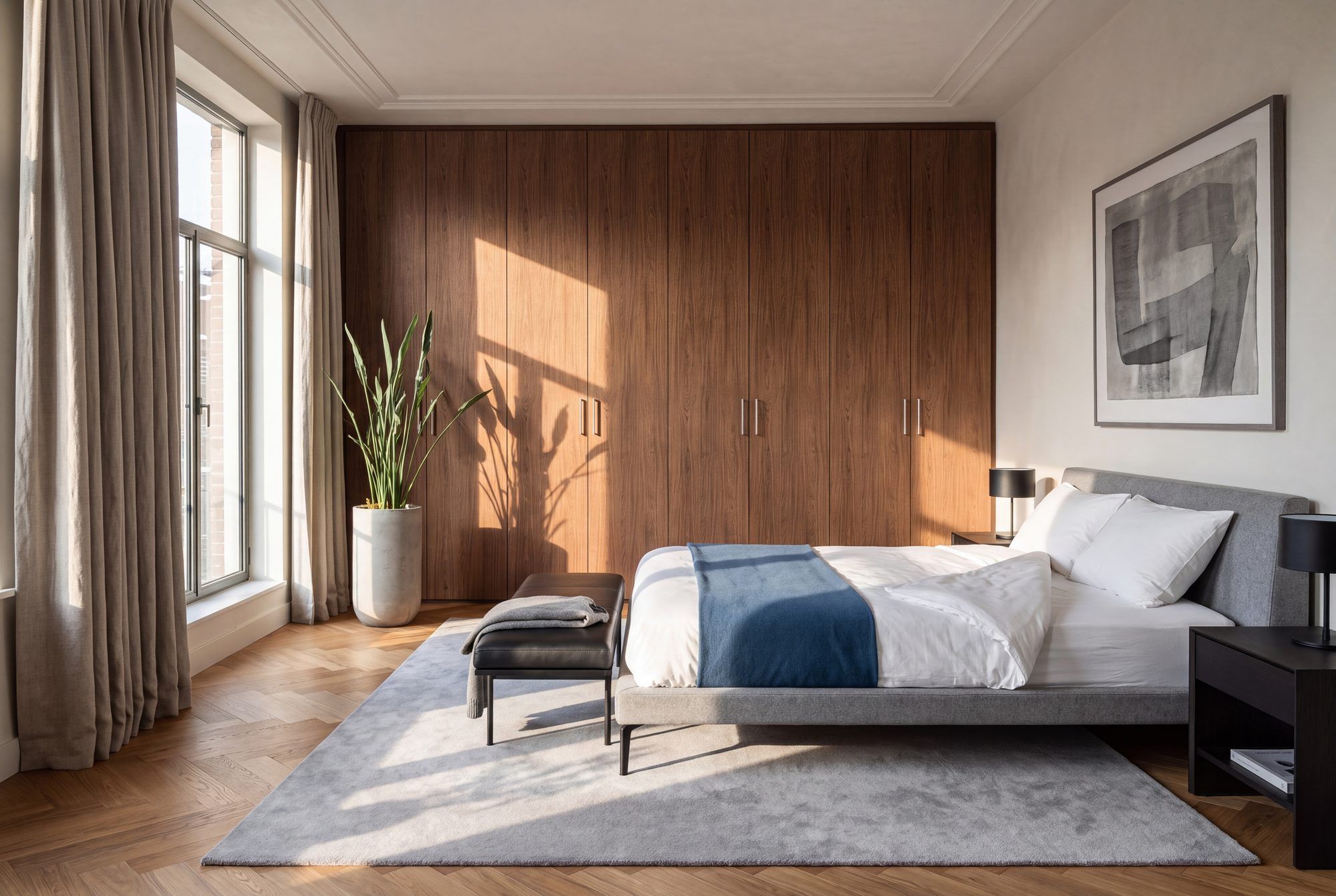 Kamerhoge draaideurkast in noten houtlook, van wand tot wand en tot aan het plafond, met slanke verticale grepen.