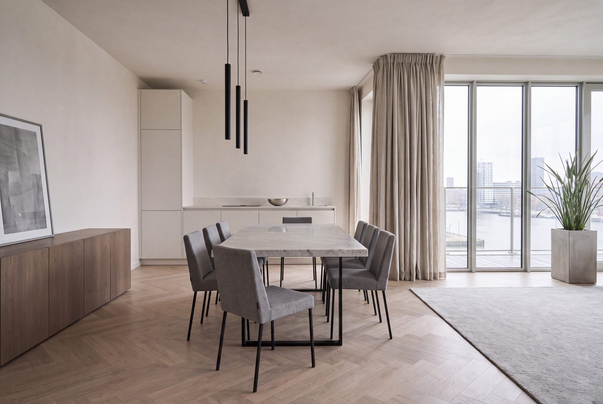 Eethoek met een rechthoekige tafel, gestoffeerde stoelen en een laag dressoir langs de wand.